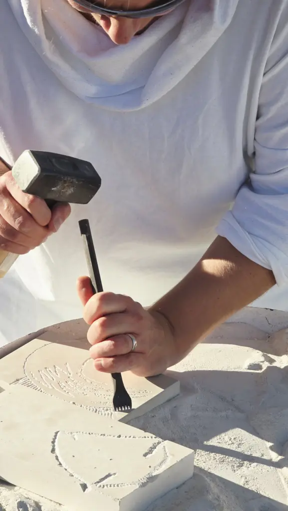 Hands carving Brač limestone with traditional stone carving tools during the Journey Through Stone workshop in Croatia.