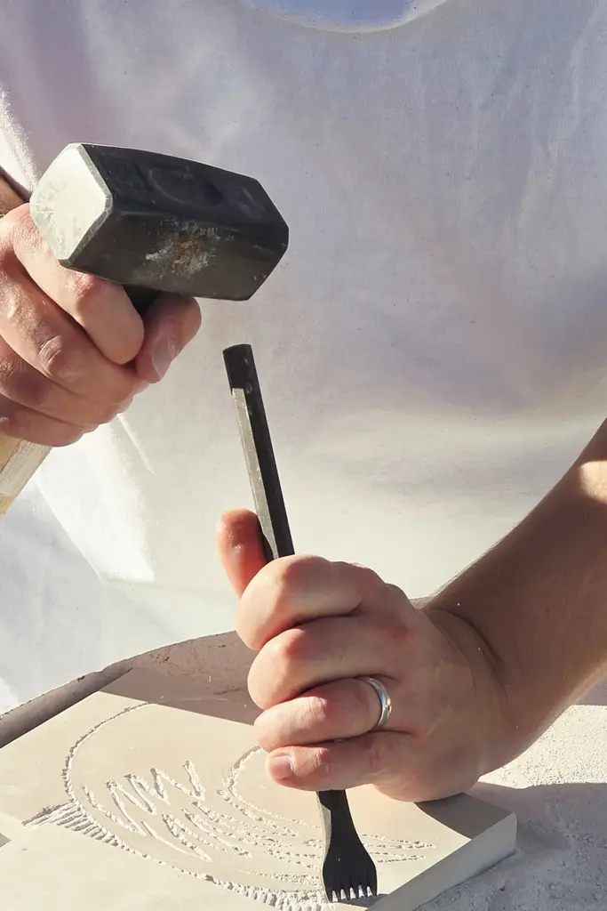 Close-up of a participant carving an angel wing relief in Brač stone using traditional hammer and chisel during the Journey Through Stone workshop