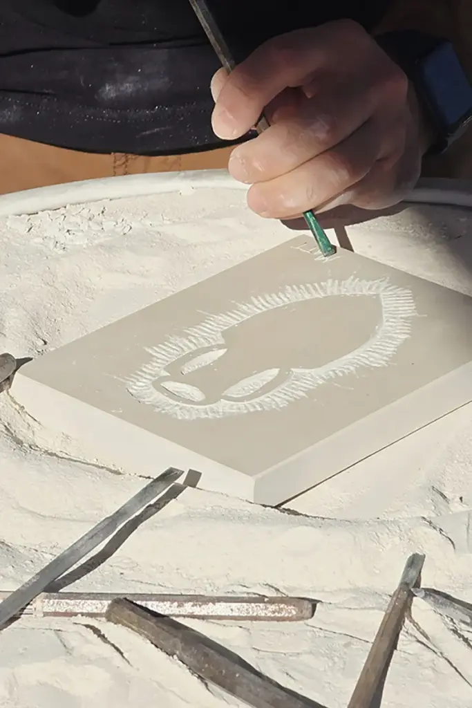 Participant carving a relief into Brač stone using traditional hand tools during the Journey Through Stone workshop on the island of Brač, Croatia.