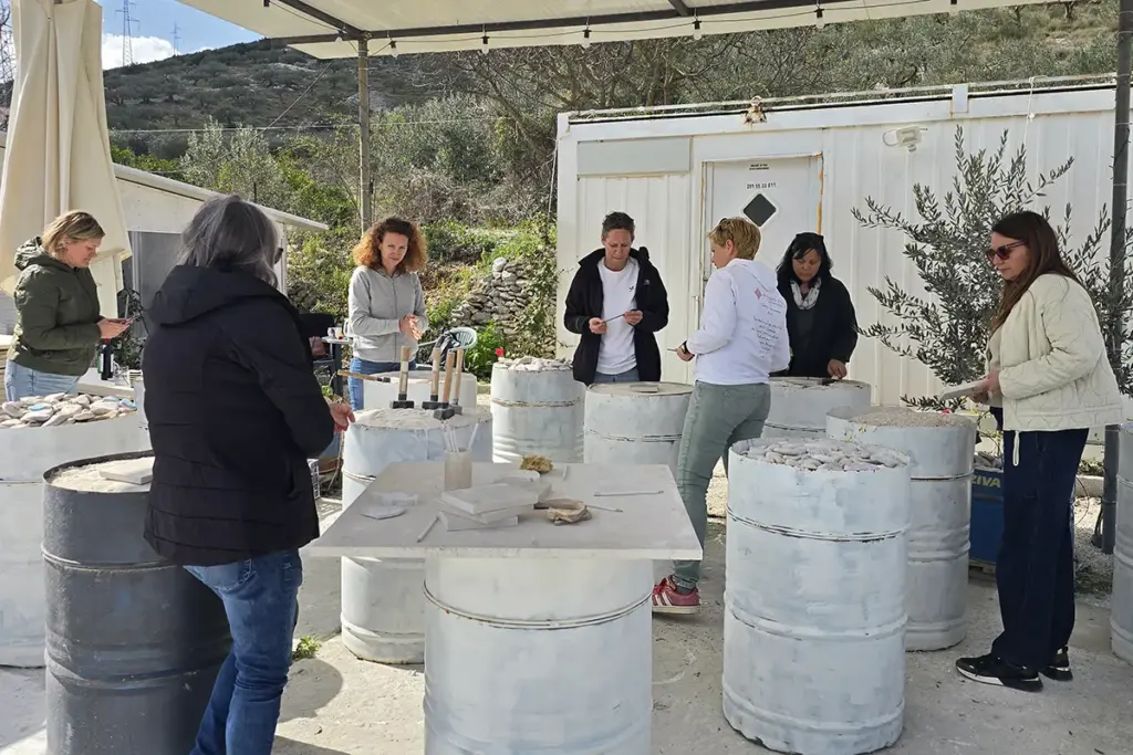 Participants learning traditional Brač stone carving during a group Journey Through Stone workshop at Kameni otok